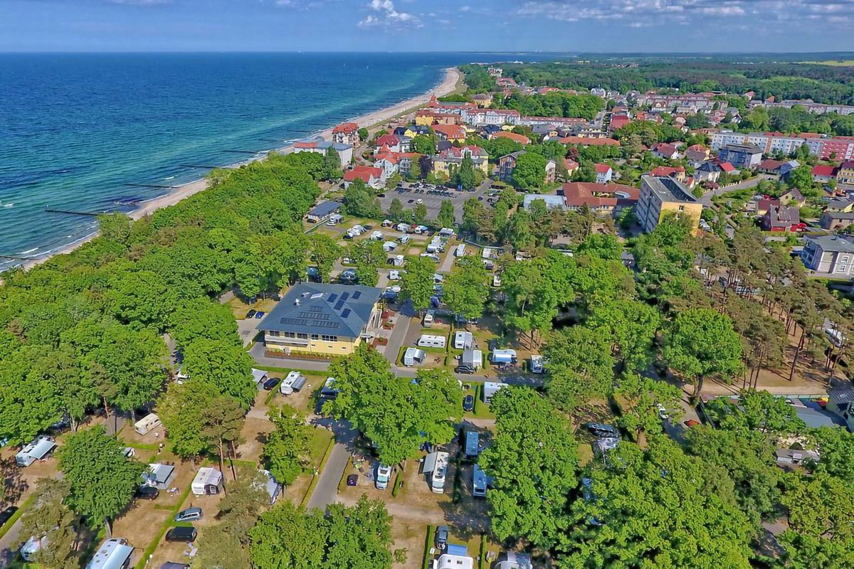 Camping.info n. 1 in Germania: il campeggio Kühlungsborn. Puoi vedere una vista aerea di un campeggio in campagna, con il mare sullo sfondo.
